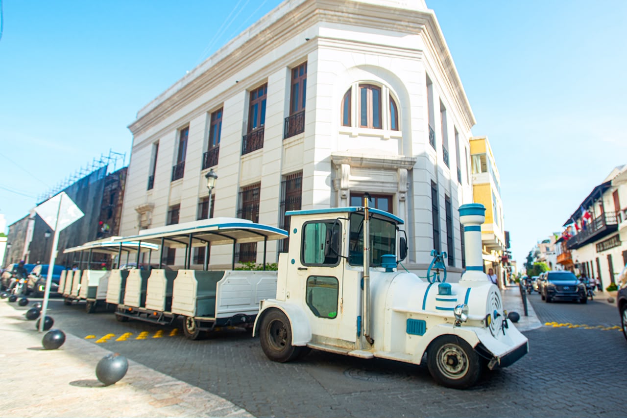 Tren turístico frente a un edificio colonial esquinero