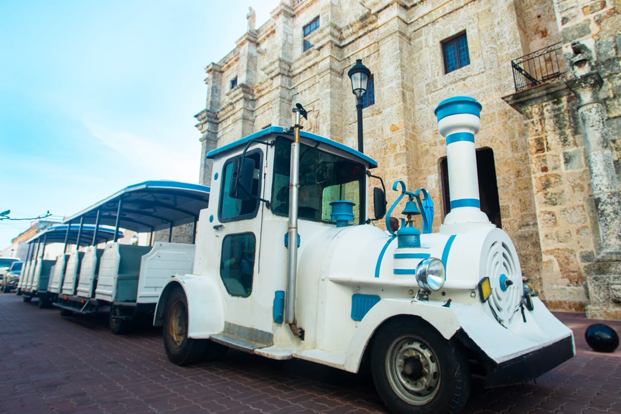 Tren turístico junto a la fachada de piedra de la Catedral Primada de América