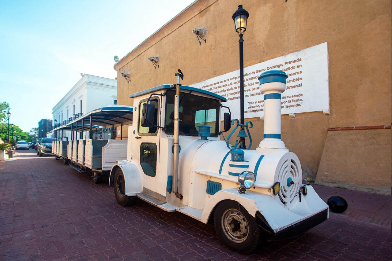 Tren turístico junto a un muro histórico de la Zona Colonial