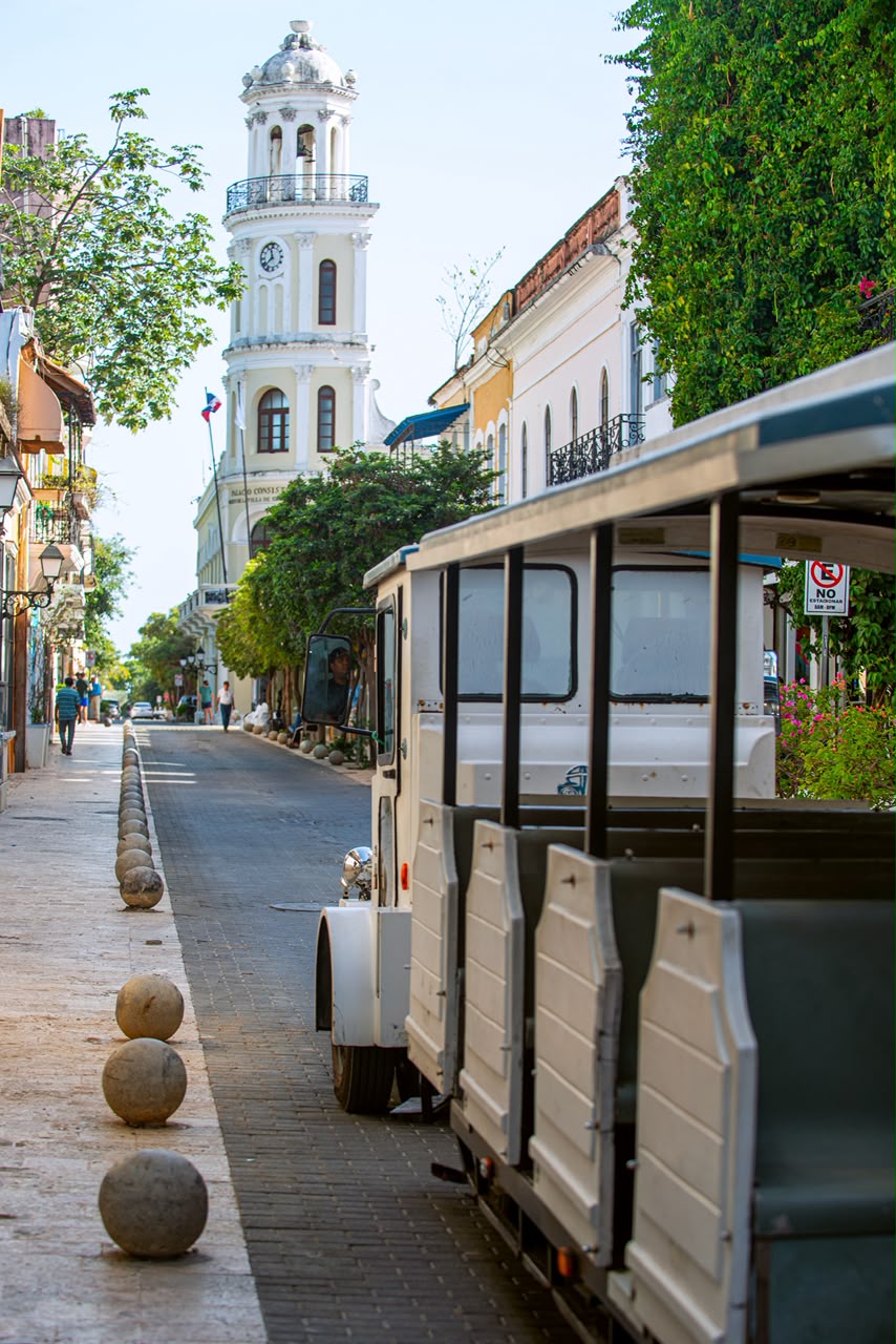Calle empedrada con vista a una torre del reloj colonial